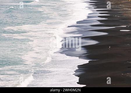 Big waves rolling on the beach with two unrecognizable people standing in the distance Stock Photo