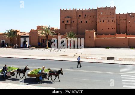 Donkey carts carrying fresh vegetables passing by the kasbah of Taourirt in the old city of Ouarzazate, Morocco. Stock Photo