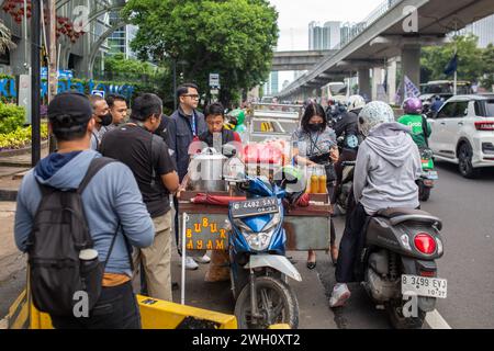 Jakarta, Indonesia - February 7, 2024: Unidentified people buying bubur ayam from a street vendor. Stock Photo