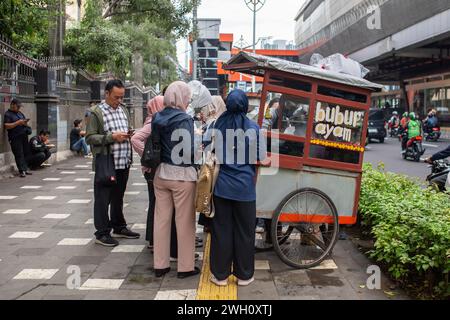 Jakarta, Indonesia - February 7, 2024: Unidentified people buying bubur ayam from a street vendor. Stock Photo