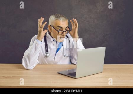Amazed male doctor shocked by online news on laptop Stock Photo
