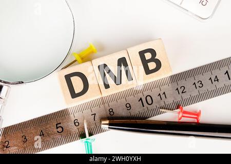 DMB text of non-wooden cubes next to a calculator, pen, measuring ruler, magnifying glass on a white background Stock Photo