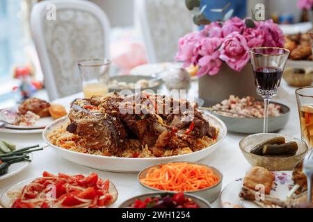 Delicious traditional Uzbek pilaf with tender lamb and fresh vegetables, served with vibrant salads and pickles. Beautifully presented with appetizing Stock Photo