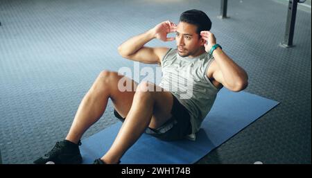 Fitness, man and doing sit ups for wellness, health and motivation doing workout routine, exercise and training in gym on floor. Male trainer, athlete Stock Photo