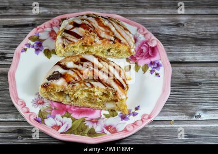 White chocolate and caramel sauce topping on a baked Danish pastry stuffed with honey sugary sweet syrup, sweet bakery dough baked in the oven with fl Stock Photo