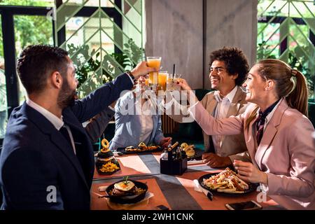 Group of businesspeople in a restaurant toasting at business lunch. Stock Photo