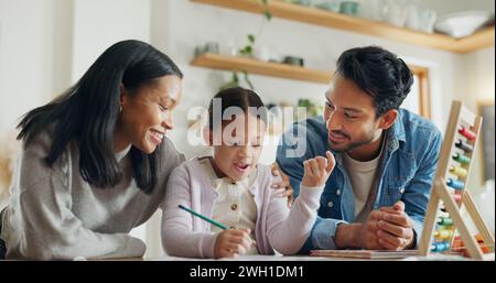 High five, girl with parents and support with learning in house with card, game or mom and dad helping with homework together in home. Child, family Stock Photo