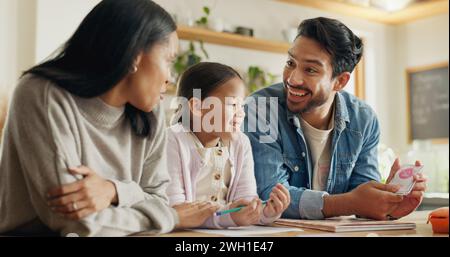 High five, girl with parents and support with learning in house with card, game or mom and dad helping with homework together in home. Child, family Stock Photo