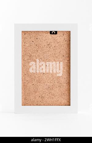 Wood frame for mockup. Simple interior with a blank frame template on white wooden shelves in front of a white wall background. Stock Photo