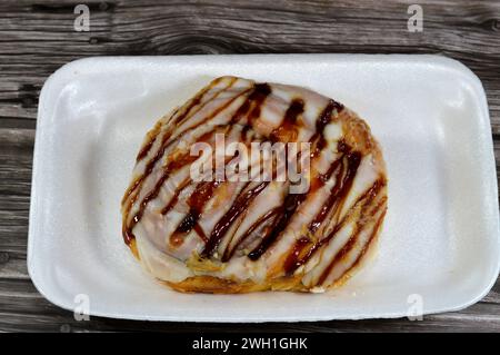 White chocolate and caramel sauce topping on a baked Danish pastry stuffed with honey sugary sweet syrup, sweet bakery dough baked in the oven with fl Stock Photo