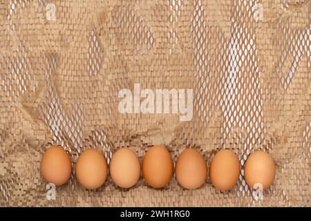 Row of different shade eggs on packing perforated paper background. Copy space simple sustainable rustic background for traditional Easter holiday car Stock Photo