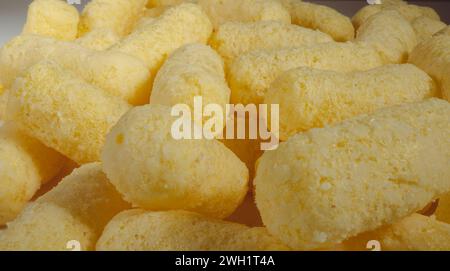 Close up of yellow air corn sticks close-up. Crunchy corn snacks texture. Selective focus. Stock Photo