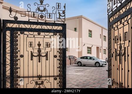 Open large double metal gate. Double wrought-iron gate. Wrought iron gate and stone pillar. Black wrought iron entrance gates to rural property. Nobod Stock Photo