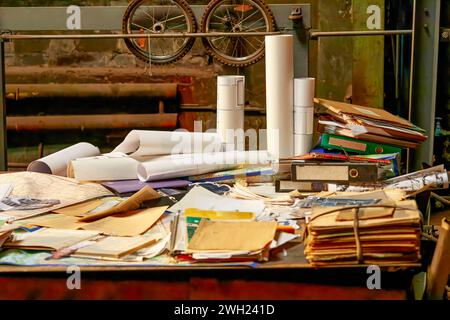 Image of a large table in a workshop littered with old drawings and folders Stock Photo