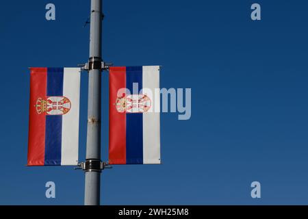 Serbian flags against the blue sky on a sunny day in the center of Belgrade. Red blue white tricolor with the symbol of the coat of arms of Serbia. Pa Stock Photo