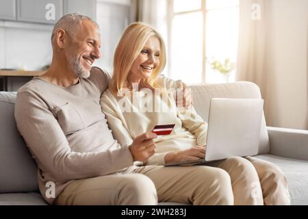 Happy loving caucasian retired man and woman shopping online together Stock Photo