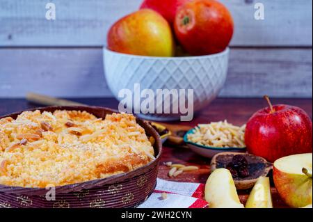 Freshly baked apple pie on a rustic kitchen worktop with ingredients and kitchen utensils. Stock Photo