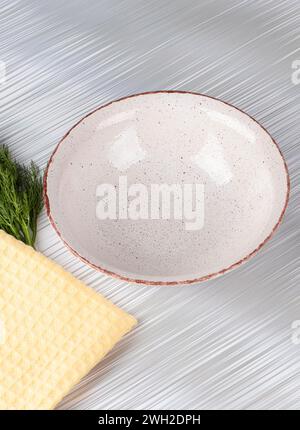 White empty deep clay plate with a spoon on a gray background. Stock Photo