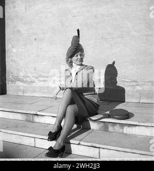 Women's fashion in the 1940s. A young woman dressed in a plaid patterned jacket and skirt. Pictured sitting in the stairs a sunny day. She is actress Dioris Söderström. Sweden 1945.  Kristoffersson Ref P73-3 Stock Photo