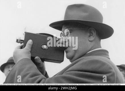 In the 1940s. A man is filming with a amateur film camera. The film was then developed and shown on a film projector on a fold up screen at home. The film had no sound. The film cameras were not battery operated and you had to wind them up like a clock to make them work. Stockholm Sweden 1946 Stock Photo