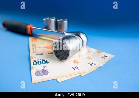 Mechanic's wrench with bills of one thousand Argentine pesos. Concept of the expensiveness of mechanics. Stock Photo