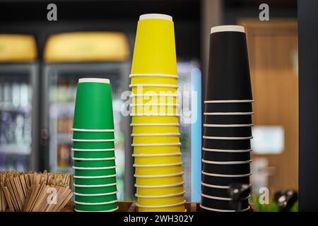 Blank three stacks of colored paper cups, green yellow black cup different sizes for hot drinks coffee, tea to take away. Mockup for coffee shop, stor Stock Photo
