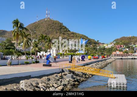 Manzanillo, Mexico  - 16 January 2024: People walking past colourful sculptures on the city's promenade Stock Photo