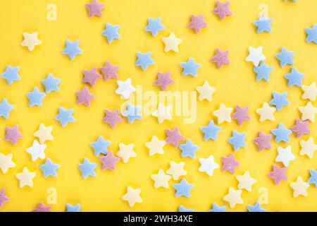 Colorful sugar sprinkles on yellow background Stock Photo