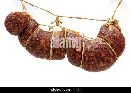 Traditional smoked sausage hanging on ropes on white background. Stock Photo