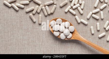 Organic dietary supplements in capsules on beige fabric background. Vitamins and natural bioadditives in tablets. Different medical pills on table. Em Stock Photo