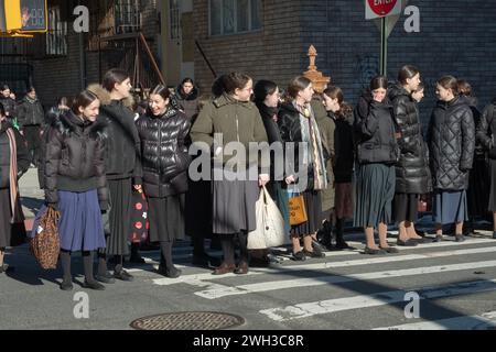 On their way to school, a large group of orthodox Jewish girls dressed modestly, wait for a light to change. In Brooklyn, New York. Stock Photo