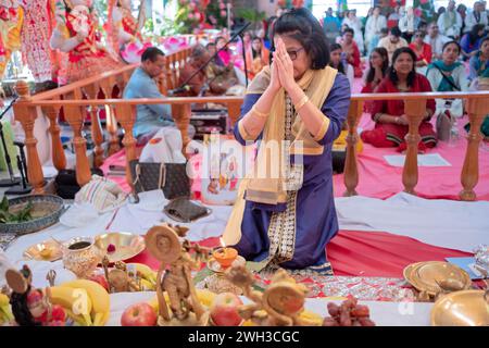 A Hindu devotee prays with her hands clasped while kneeling at the altar at a temple in Jamaica, Queens, New York City. Stock Photo