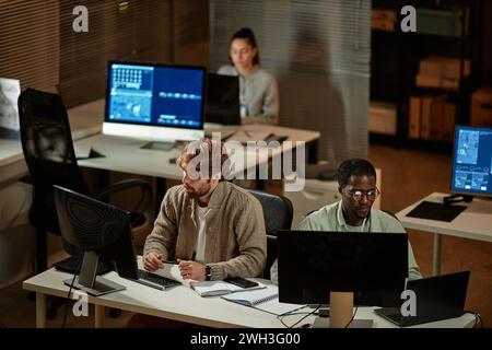 High angle view at IT developers office with people working at night and using computers, copy space Stock Photo