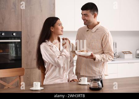 Happy young couple having breakfast in kitchen Stock Photo