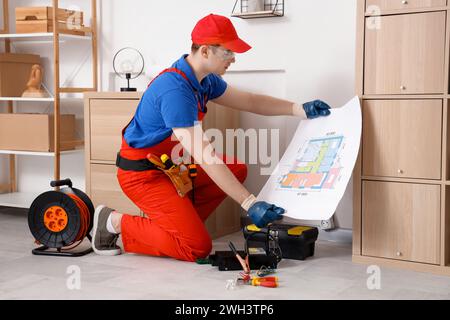 Male electrician with house plan in room Stock Photo