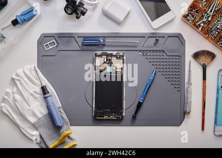 Flat lay shot of parts of disassembled cell phone and work tools displayed on table before repairing Stock Photo