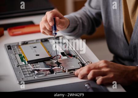 Unrecognizable engineer using screwdriver repairing element of disassembled laptop Stock Photo