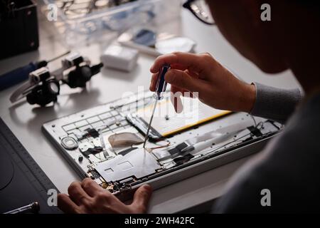 Unrecognizable male technician repairing computer using screwdriver in modern workshop Stock Photo