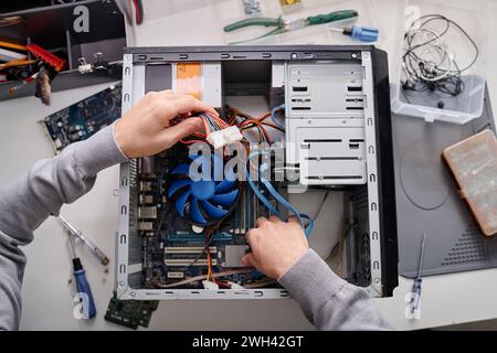 Hands of unrecognizable male repairman arranging wires in disassembled system unit of computer Stock Photo