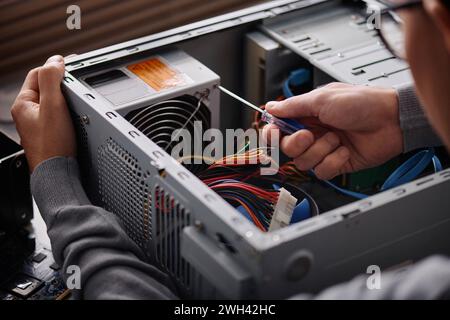 Unrecognizable electronic repairman fixing system unit tightening cogs with screwdriver Stock Photo