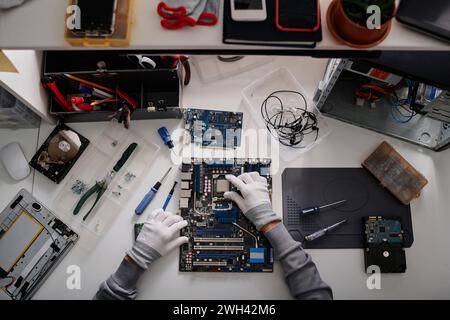 Technician working on installation of CPU into disassembled computer sitting at his desk in workshop Stock Photo