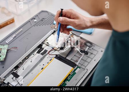 Unrecognizable caucasian man using wireless soldering iron for fixing malfunctioning PC element Stock Photo