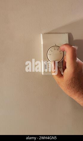 person using the thermostat placed on the wall to have an ideal temperature. Stock Photo