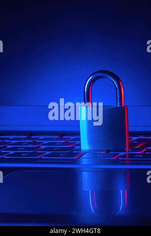 vertical photo of a closed padlock and a computer keyboard with blue background concept security and cyber attack internet Stock Photo