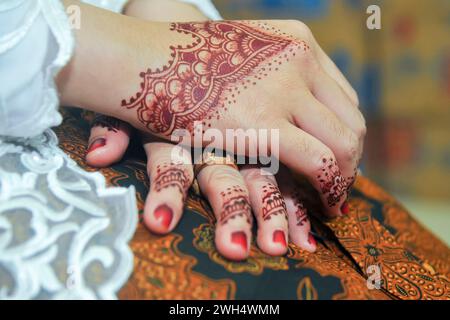 two hands decorated with henna art at a traditional Javanese wedding, Indonesia Stock Photo