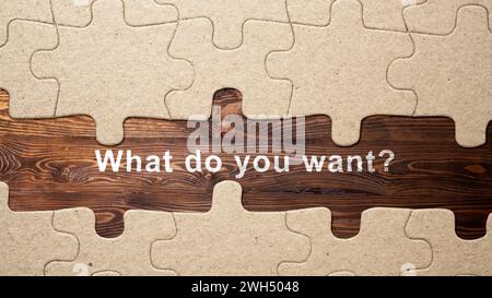 Jigsaw puzzle piece with text of 'What do you want?' on a wooden background. Business and marketing concept Stock Photo