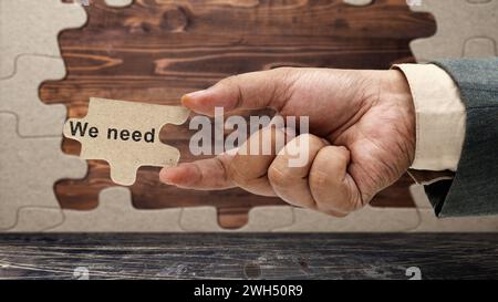 Business hand holding pieces of a jigsaw puzzle with 'We need' text. Business and marketing concept Stock Photo