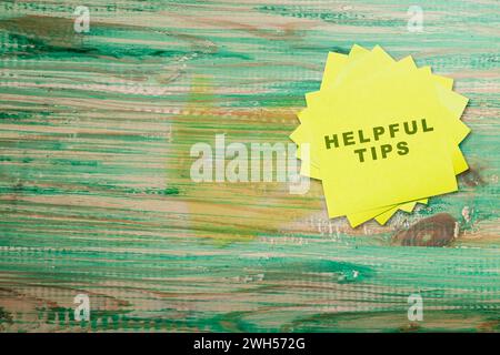 Stack of note paper with 'Helpful tips' text on a wooden background. Tips and advice concept Stock Photo