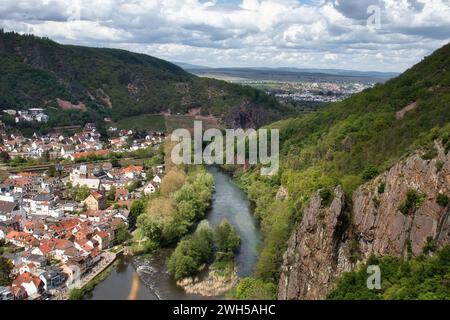 Bad Munster, Germany - May 12, 2021: Sun shining on the Nahe River next to a cliff and the town of Bad Munster on a spring day in Germany. Stock Photo