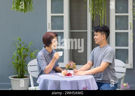 Happy asian retired mother with her adult son are relax talking together in morning. Stock Photo